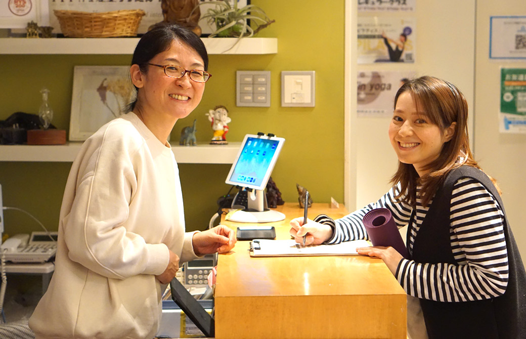 受付を挟んでカメラ目線のスタッフ